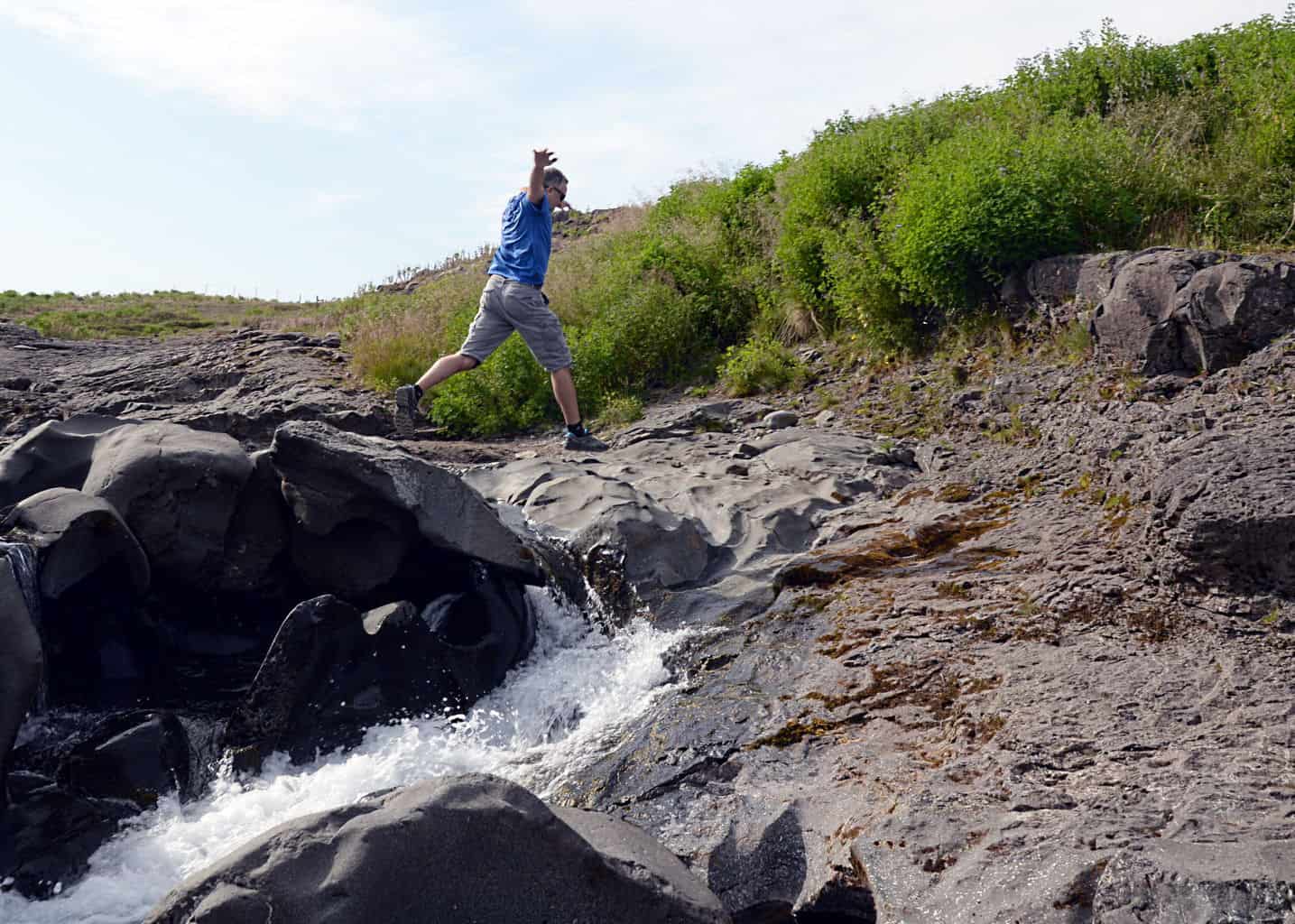 Sean jumping off rocks at a river and waterfalls in northern Iceland